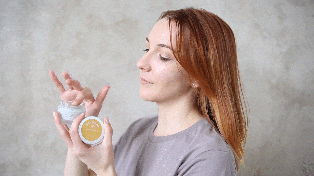 Woman opens a jar of "Indie Botanicals" lemon cream moisturizer.