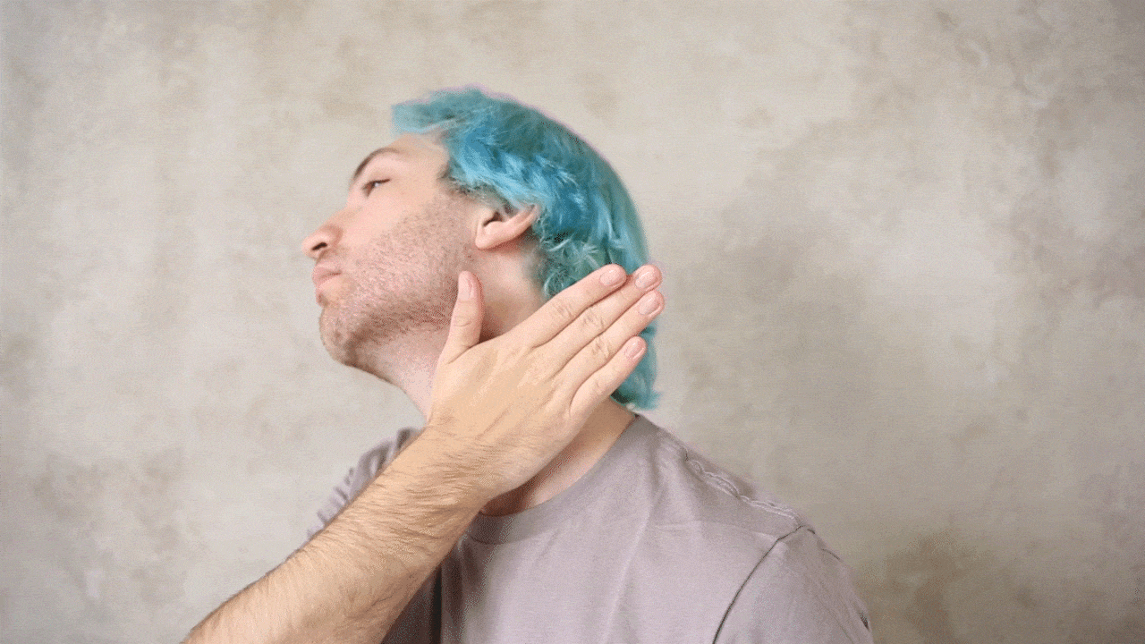 "Man with blue hair checks his jawline for stubble."