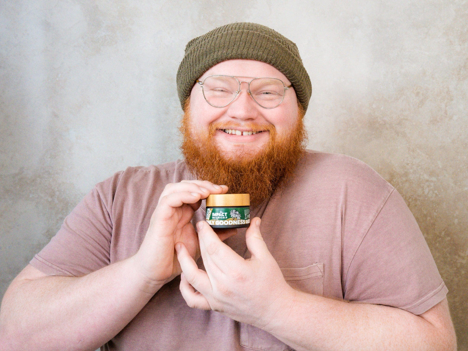 Smiling man with a beard holds a small jar of "Only Goodness" moisturizer.