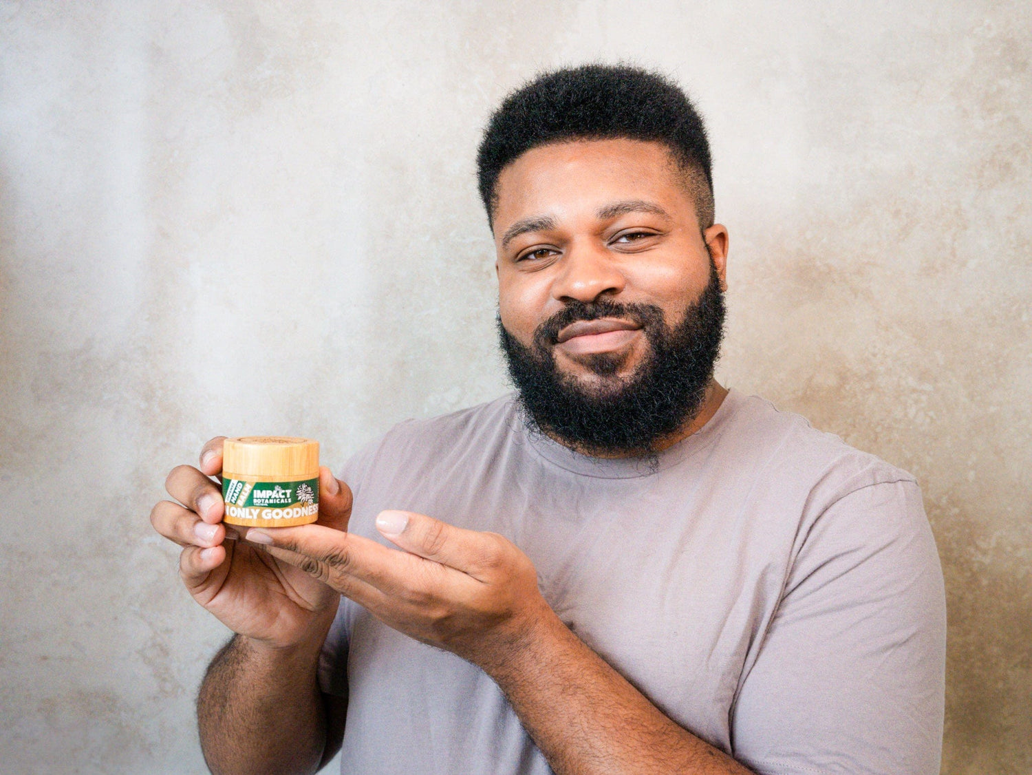 Man holds a bamboo jar of Impact Botanicals hand cream, showcasing the brand&