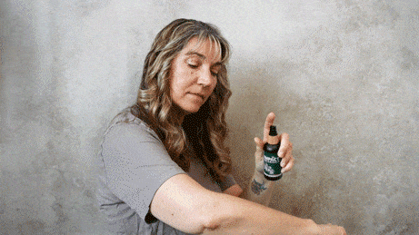Woman sprays a natural bug repellent on her arm to protect against insects.