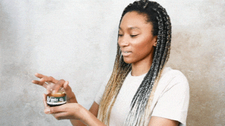 Woman opens a small jar of VEDA Wellness skincare product.