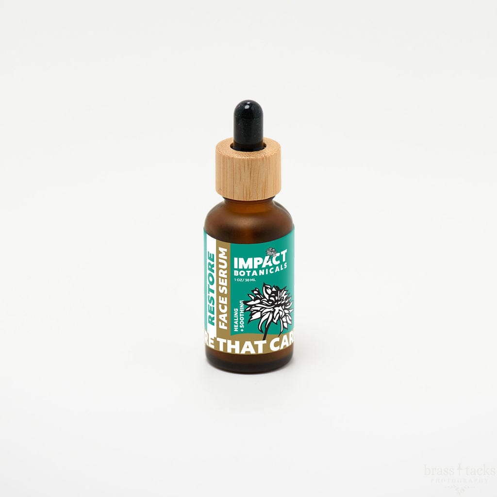 Amber bottle of Impact Botanicals Restore Face Serum with a bamboo dropper top stands against a white background.